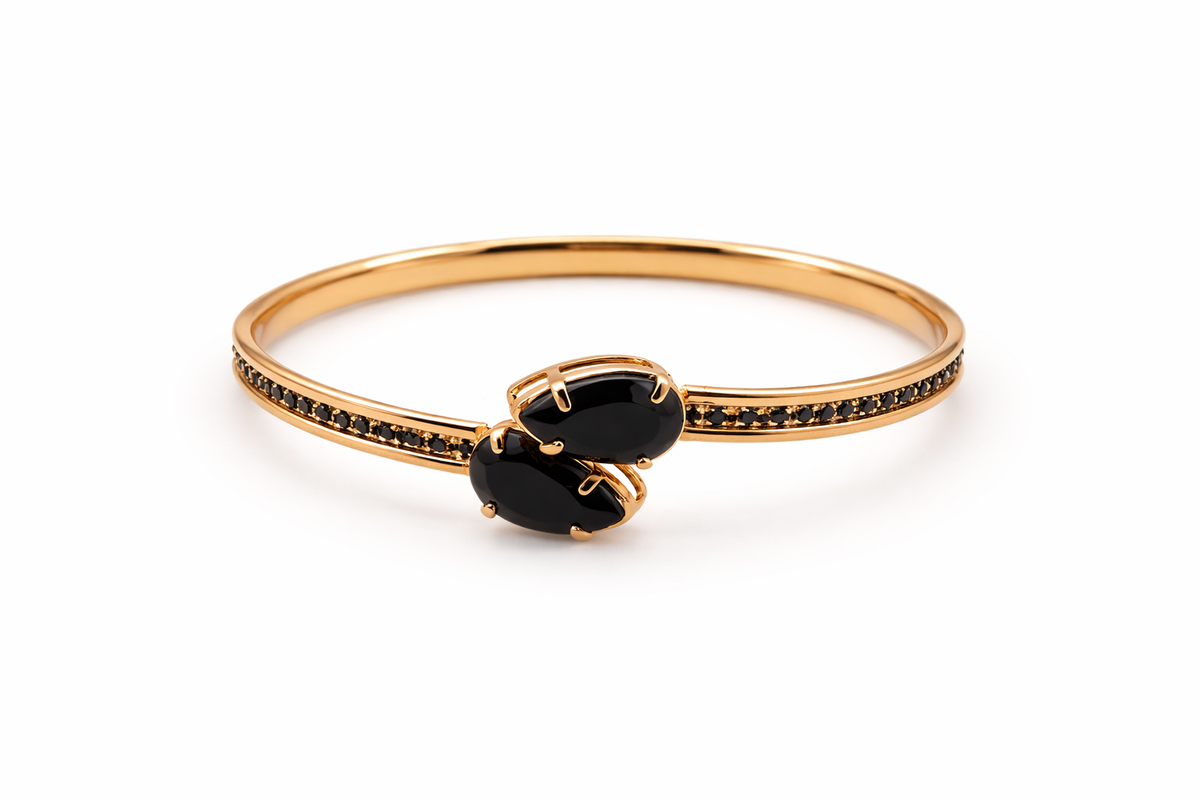 Gold bracelet with black gemstones on a white background