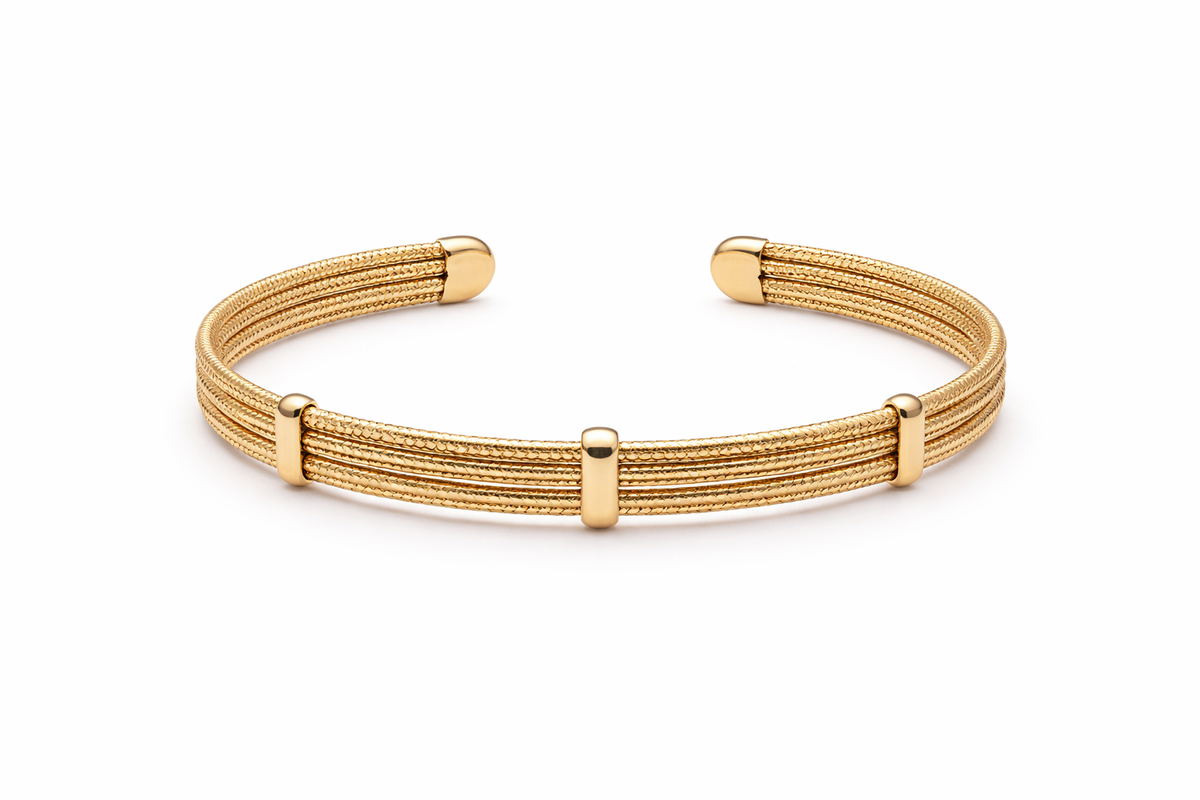 Elegant gold multi-line textured cuff bracelet worn by a modern bride standing beside a floor-to-ceiling hotel window while holding a bouquet of white roses. Soft morning sunlight, luxury bridal suite, satin wedding gown, and editorial wedding styling create a timeless bridal jewelry look.