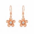 Rose gold plumeria flower drop earrings featuring polished five-petal blooms with sparkling clear center stones. The earrings hang from delicate fishhook wires and are displayed symmetrically on a pure white background, highlighting their tropical-inspired design and warm rose gold finish.
