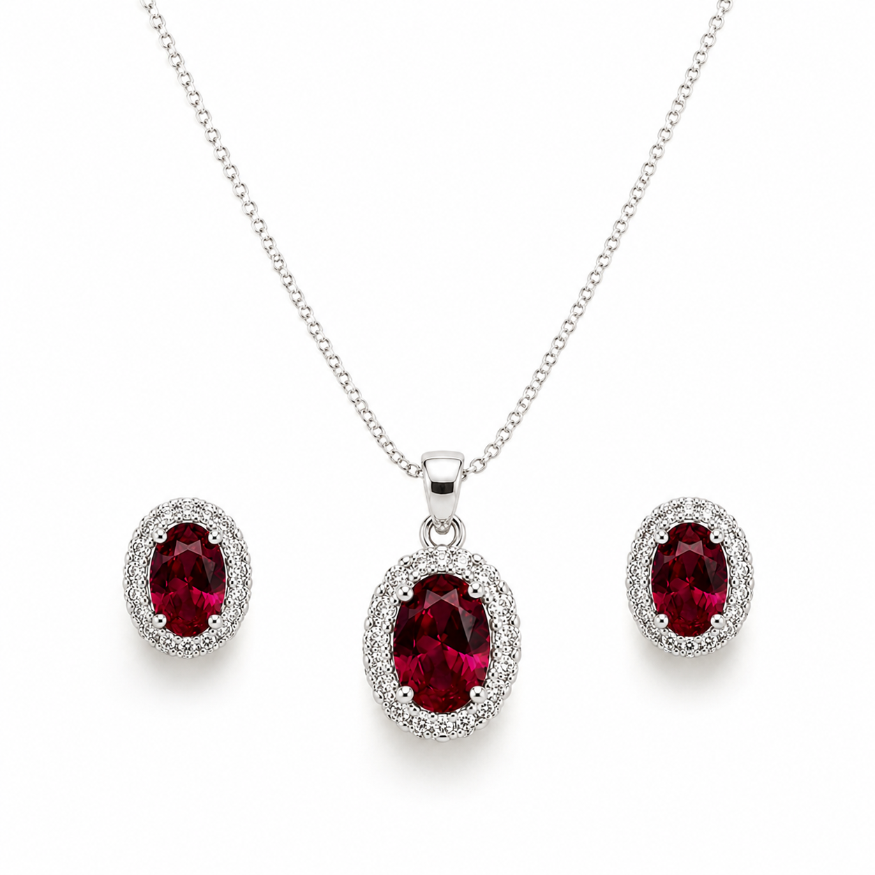 Red oval halo jewelry set featuring a sterling silver curb chain necklace with a sparkling oval red gemstone pendant and matching halo stud earrings on a pure white background.