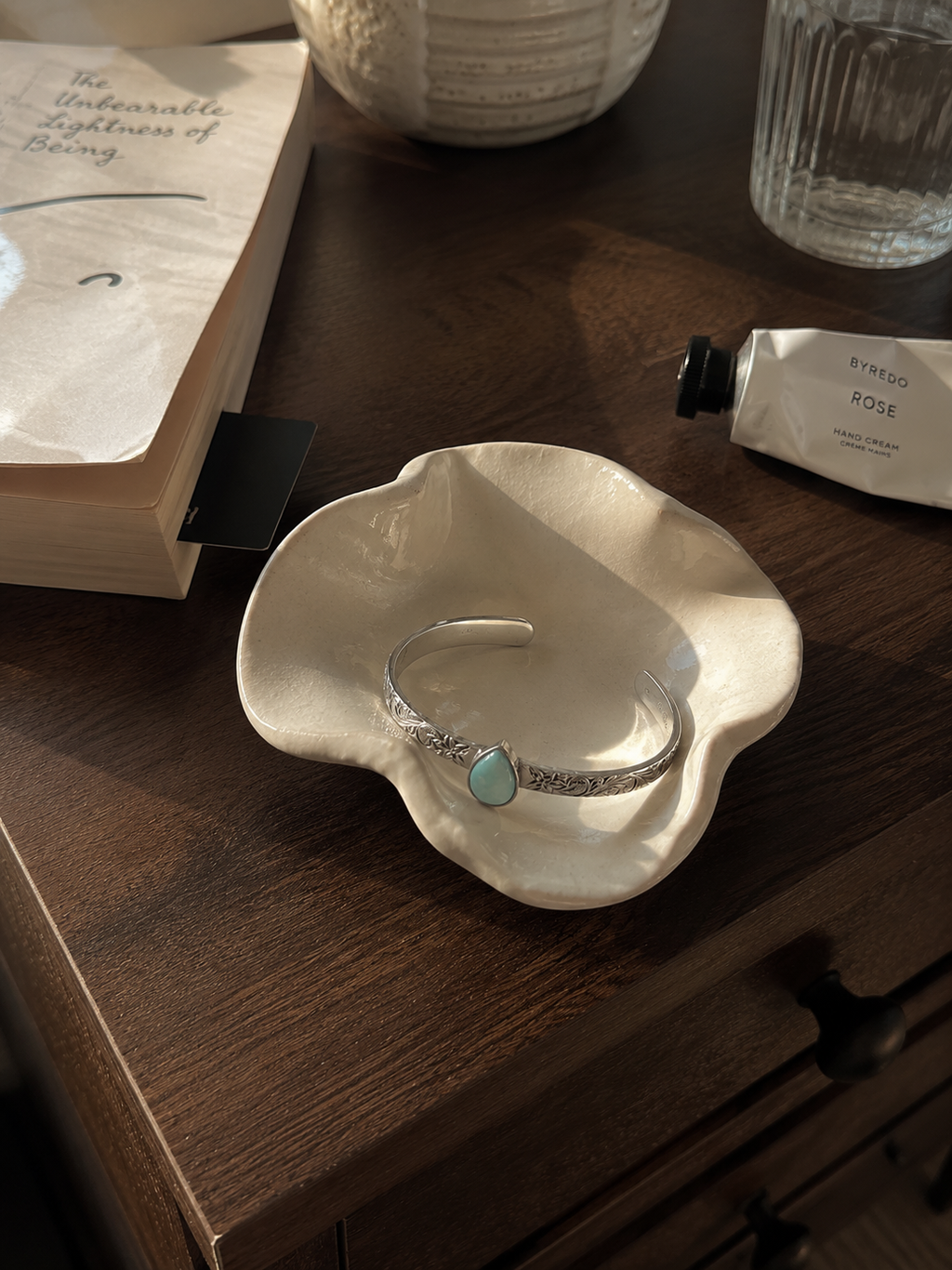 Sterling silver cuff bracelet with a natural turquoise teardrop gemstone in a ceramic bowl