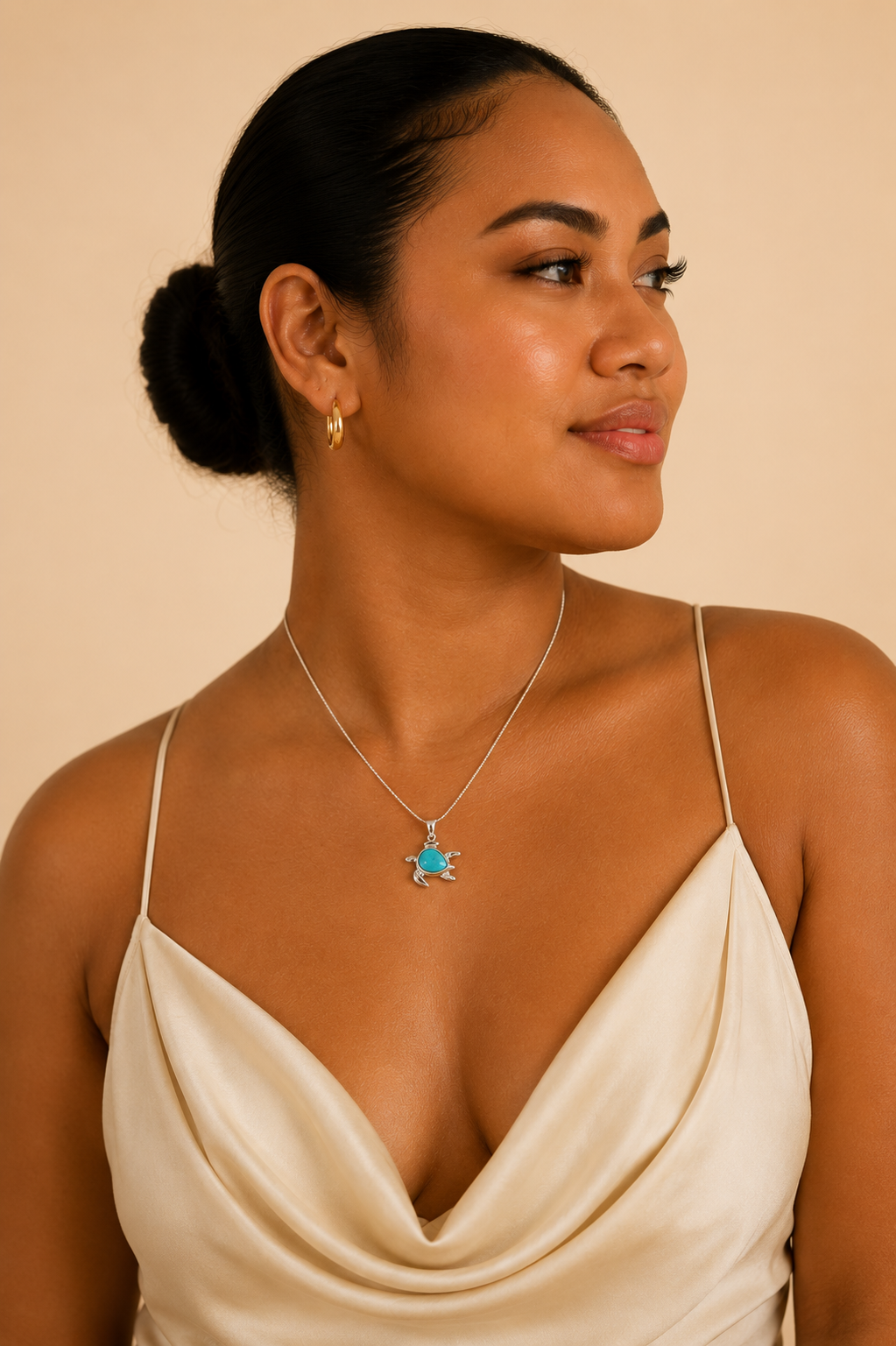 Woman wearing a beige dress with thin straps and a necklace with a blue pendant on a beige background